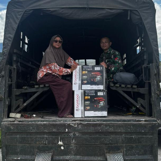 Two people sitting in the back of a large black truck with a scenic background.