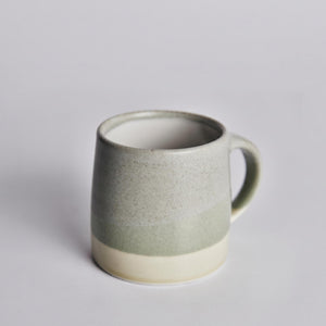 Green ceramic KINTO mug on a light gray background