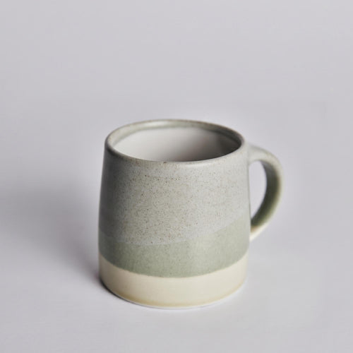 Green ceramic KINTO mug on a light gray background