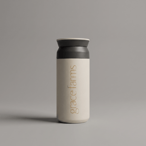 KINTO travel tumbler in white, featuring the vertical white text 'grace farms' on the front, set against a solid gray background.