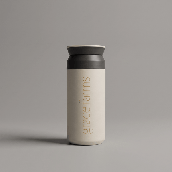 KINTO travel tumbler in white, featuring the vertical white text 'grace farms' on the front, set against a solid gray background.