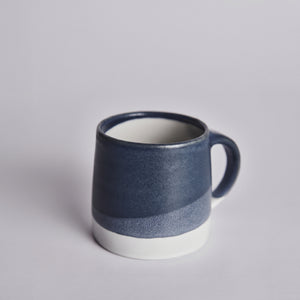 Blue ceramic KINTO mug with white base on a light gray background